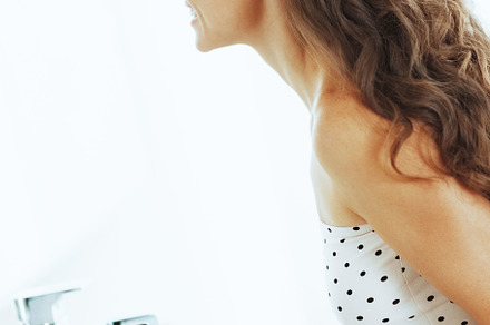 Happy young woman looking in mirror in bathroom, a Person Photo by Alliance Images