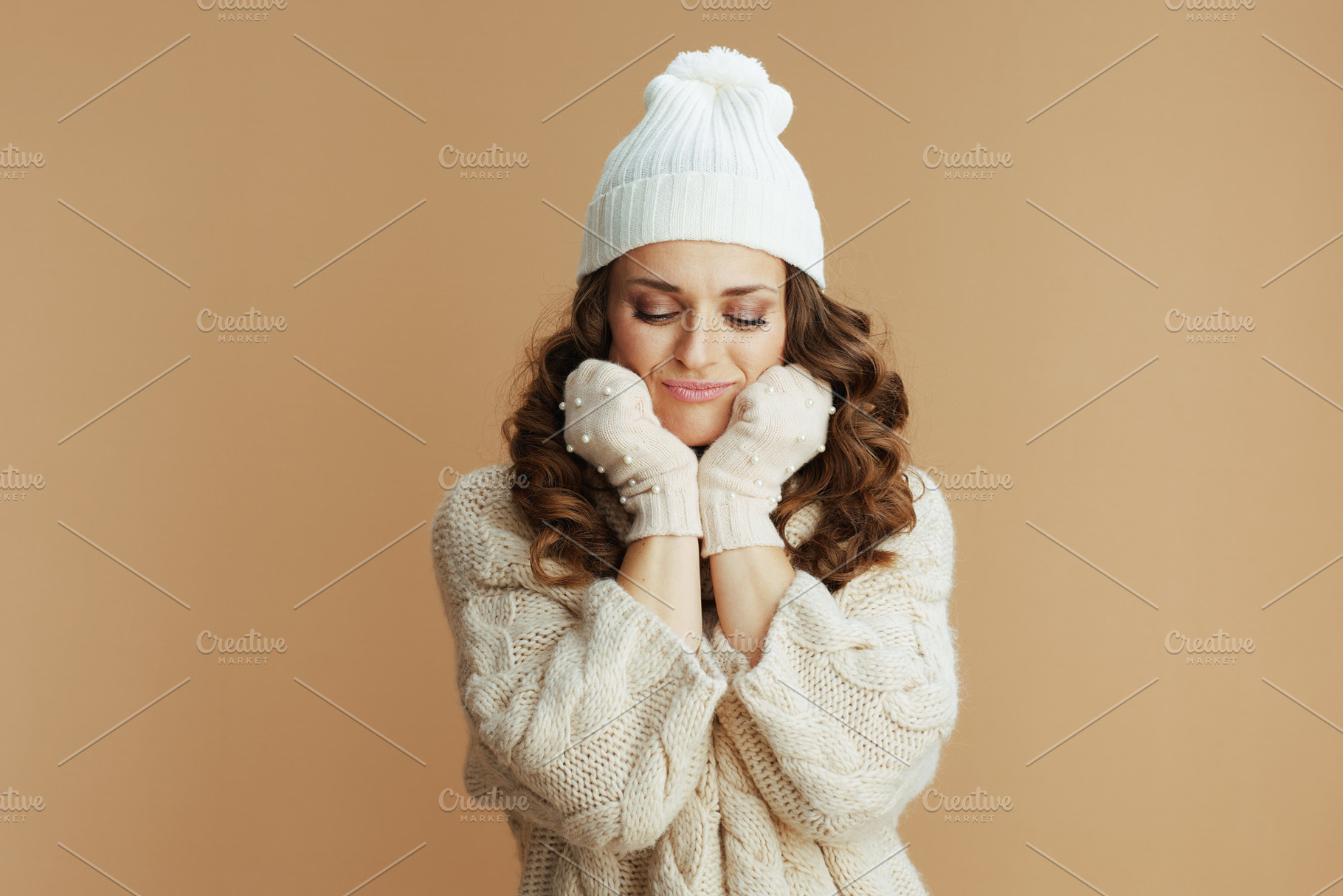 sad elegant woman in beige sweater, mittens and hat on beige, a Person Photo by Alliance Images