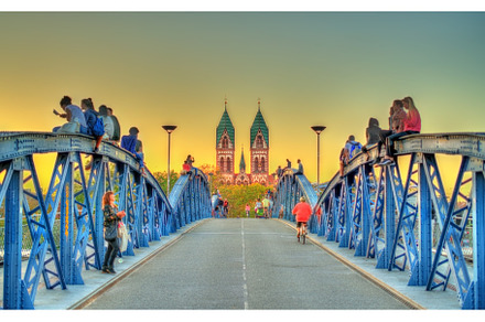 Young people sit on the Wiwili bridge in Freiburg im Breisgau, Germany, an Architecture Photo by Leonid Andronov