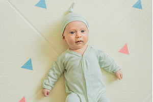 Adorable baby in a green hat lying, a Person Photo by Elizaveta Galitskaya