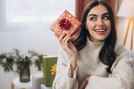 Beautiful happy woman unwrapping New Year or Christmas presents