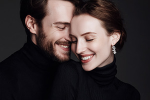 Smiling couple embracing in black turtlenecks, celebrating love, a Photo by Studio ANNA