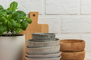 Kitchen table setting featuring stacked bowls, fresh basil, and, a Food & Drink Photo by Olena Rudo