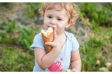 A child eats bread in the park, a Person Photo by yanadjana
