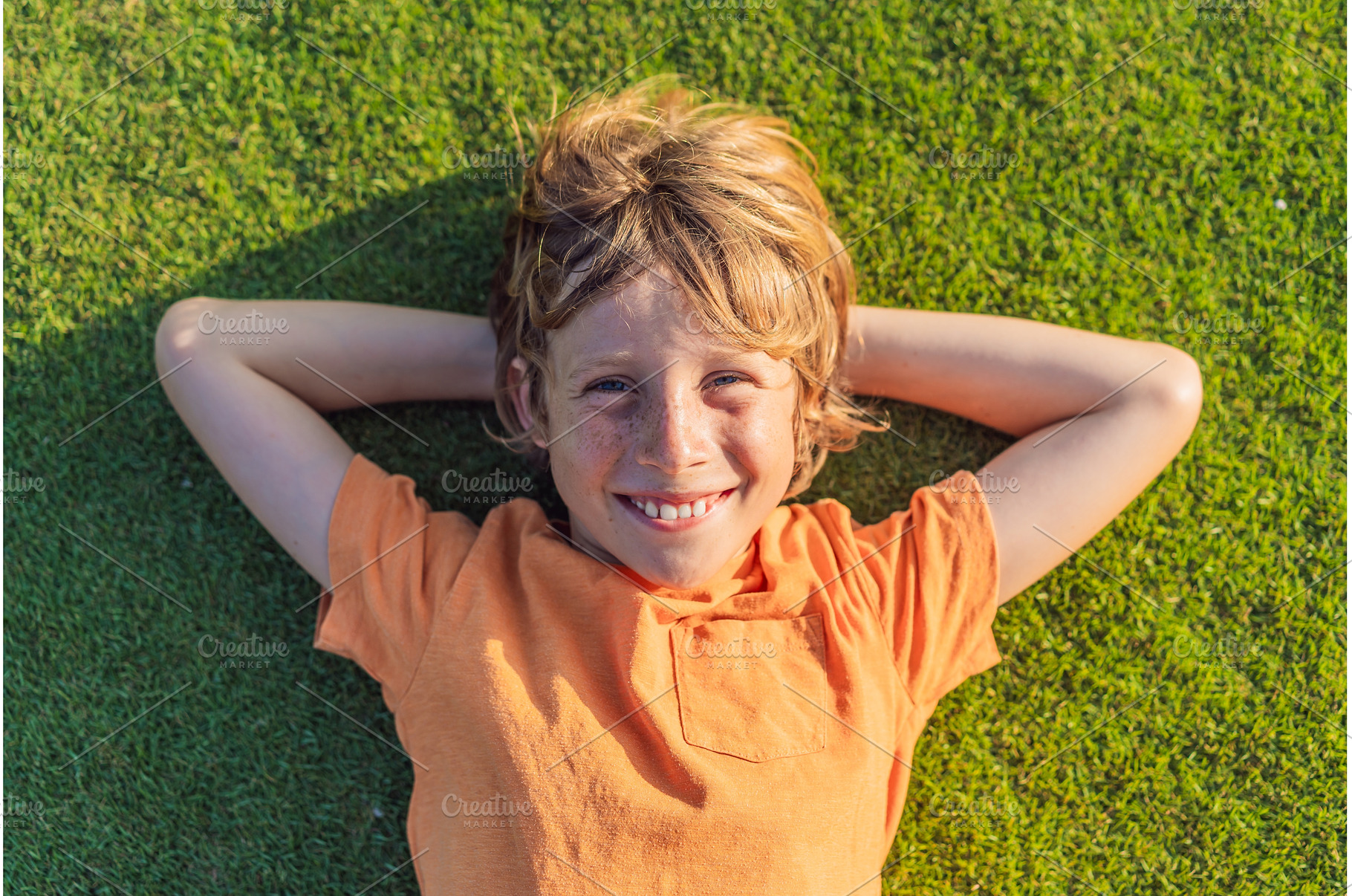 Boy lying on green grass looking at, a Nature Photo by Elizaveta Galitskaya