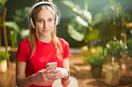 woman in fitness clothes in green living room using phone, a Person Photo by Alliance Images