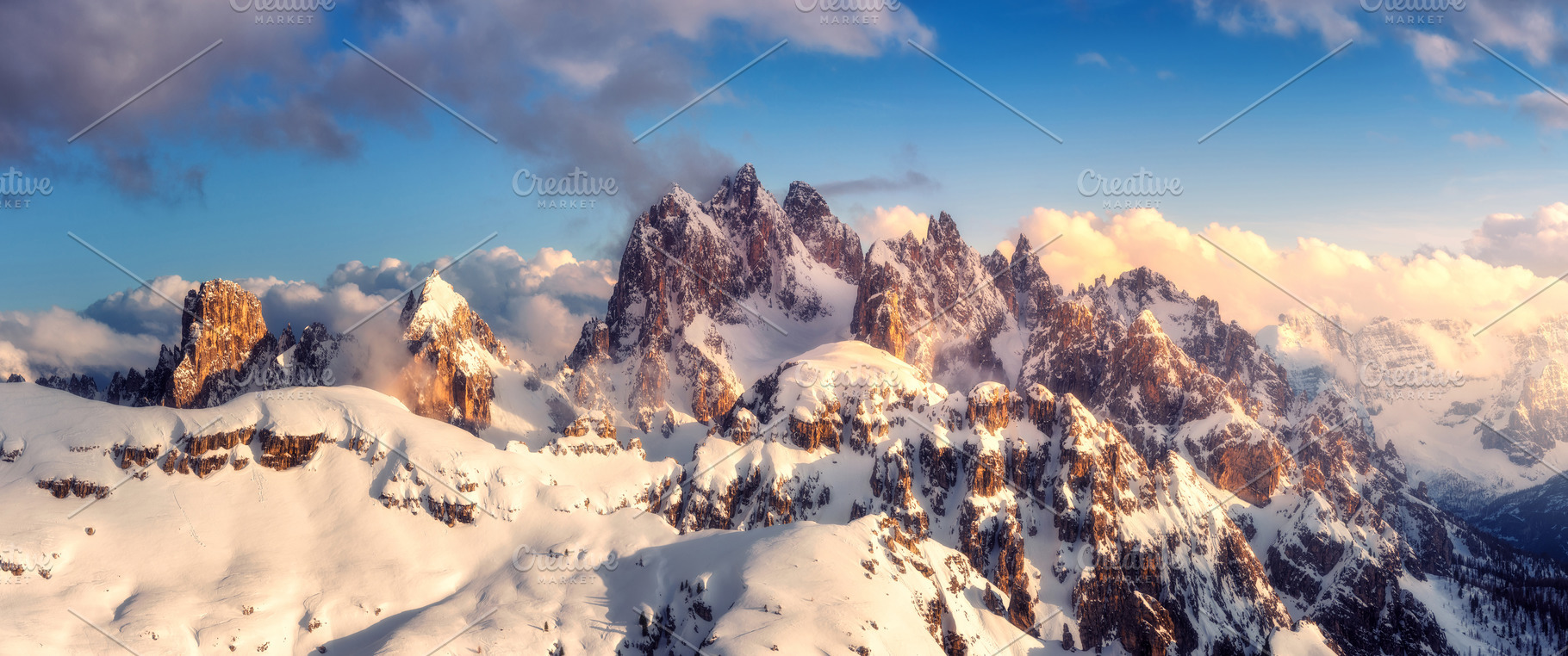Snowy mountains in low clouds and blue sky at sunset in winter, a Nature Photo by den-belitsky