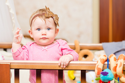 A baby in the crib looks at the camera featuring cute, childhood, and bed