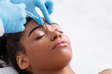 Young black woman receiving botox in, a Photo by Prostock-Studio