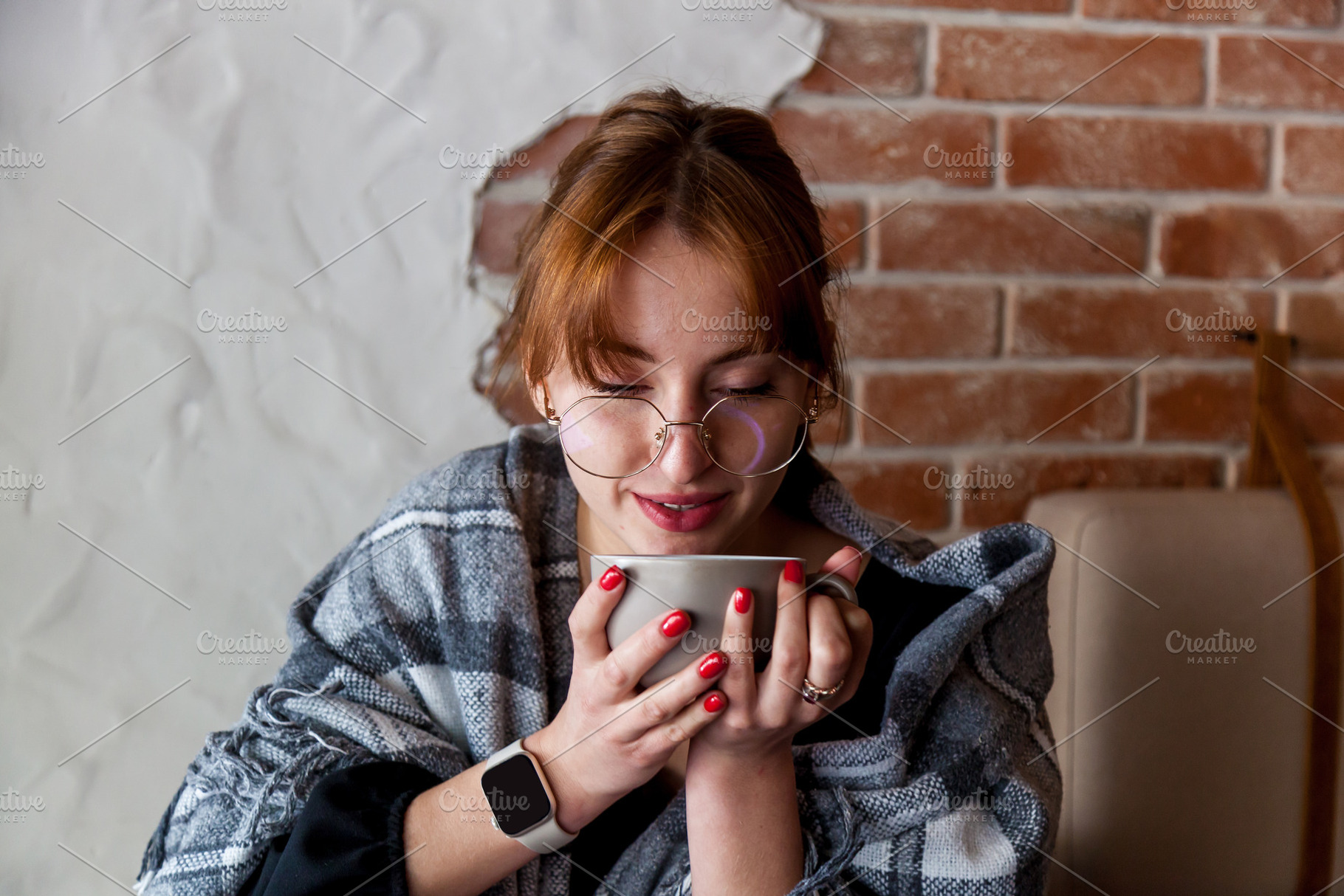 Woman in glasses wrapped in blanket enjoying hot drink indoors, a Person Photo by Photostock