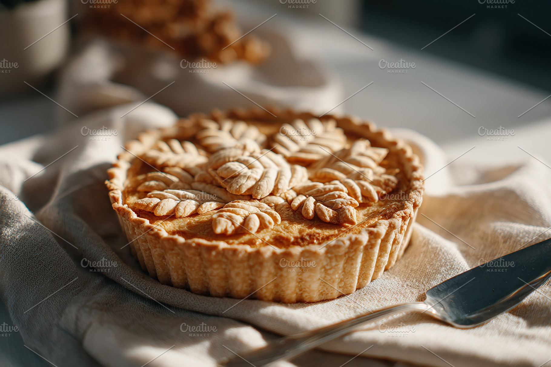 Delicious dessert pie with intricate leaf design on a linen cloth in warm sunli, a Photo by AlyaAnd