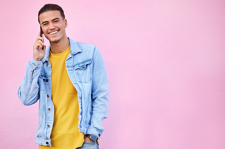 Phone call, happy and portrait of a man in a studio with a casual, trendy and stylish outfit. Happy, smile and male model on mobile conversation with cellphone by a pink background with mockup space., a Photo by Peopleimages.com