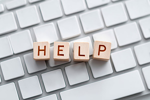 Wooden blocks spelling help on a keyboard during a tech issue in an office sett, a Photo by AlyaAnd