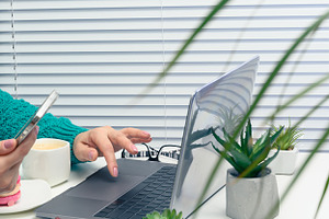 A woman working on a laptop and using a smartphone, an office de, a Person Photo by ndanko