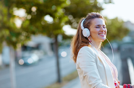 smiling elegant woman in pink dress and white jacket in city, a Person Photo by Alliance Images