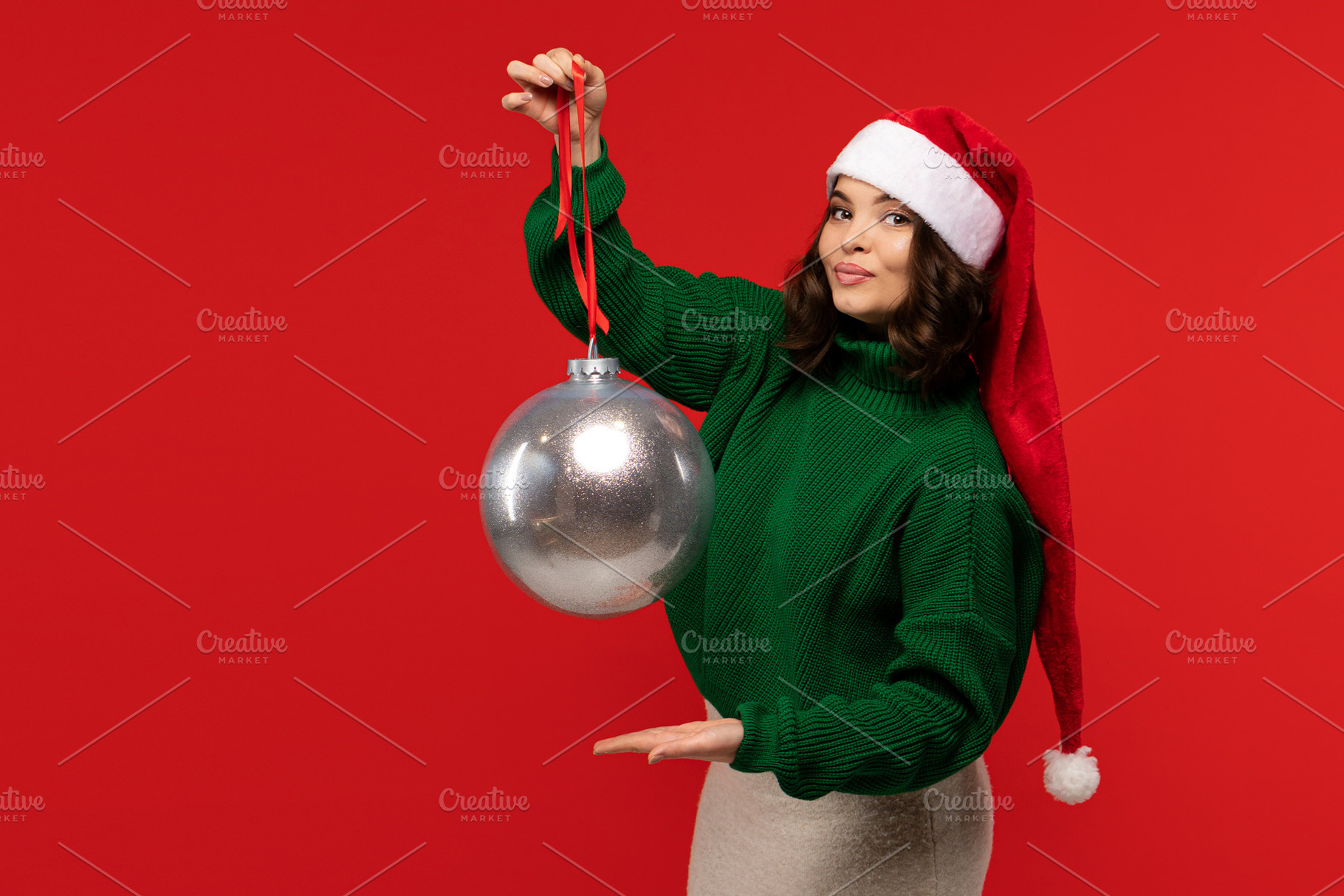 Woman in Santa hat holding ball, a Person Photo by Elena Vagengeim