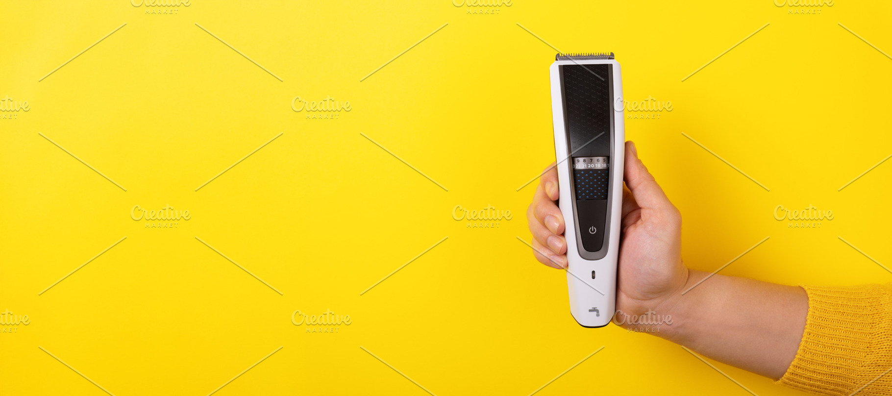Hand holding a modern electric hair trimmer upright against brig, a Beauty & Fashion Photo by Ales Munt