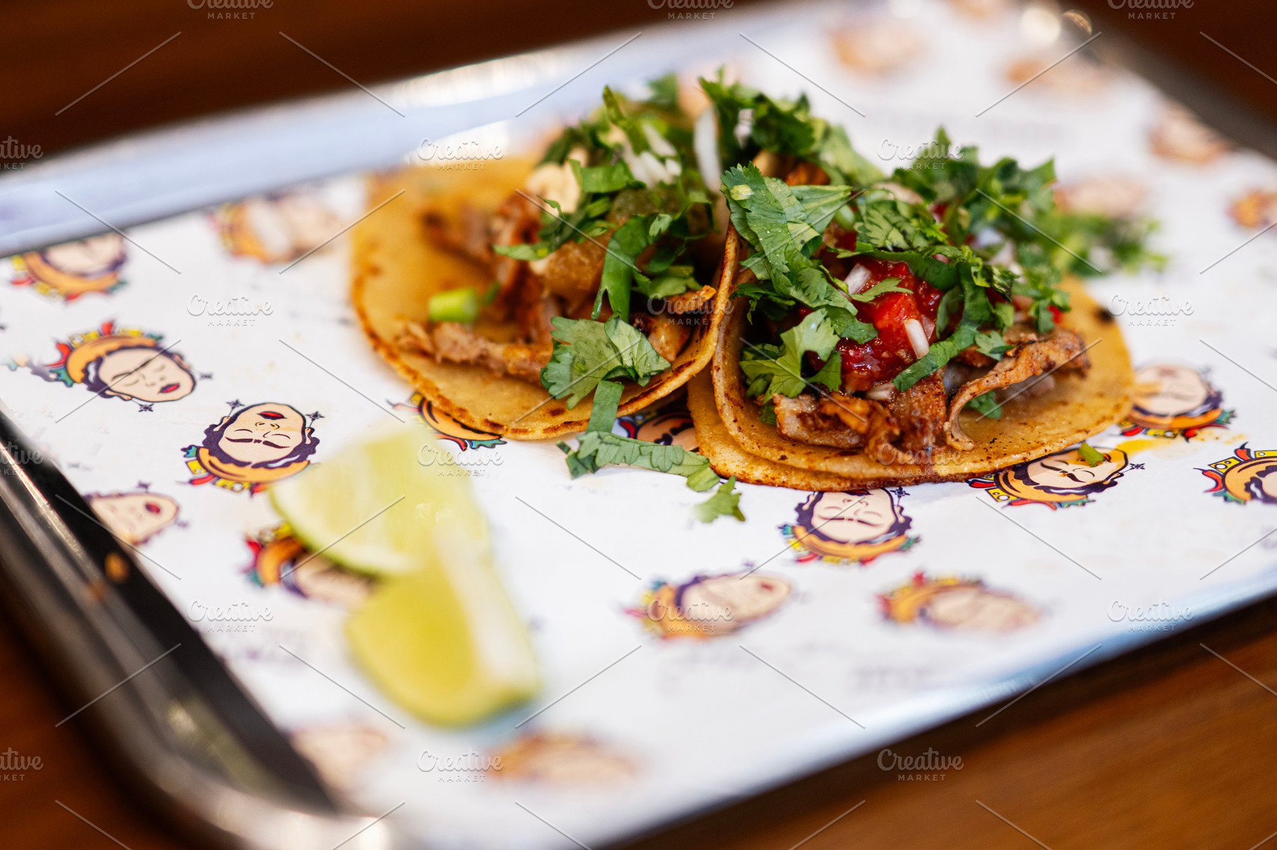 Fresh tacos served with cilantro, salsa, and lime on a decorated tray, a Photo by AS photostudio