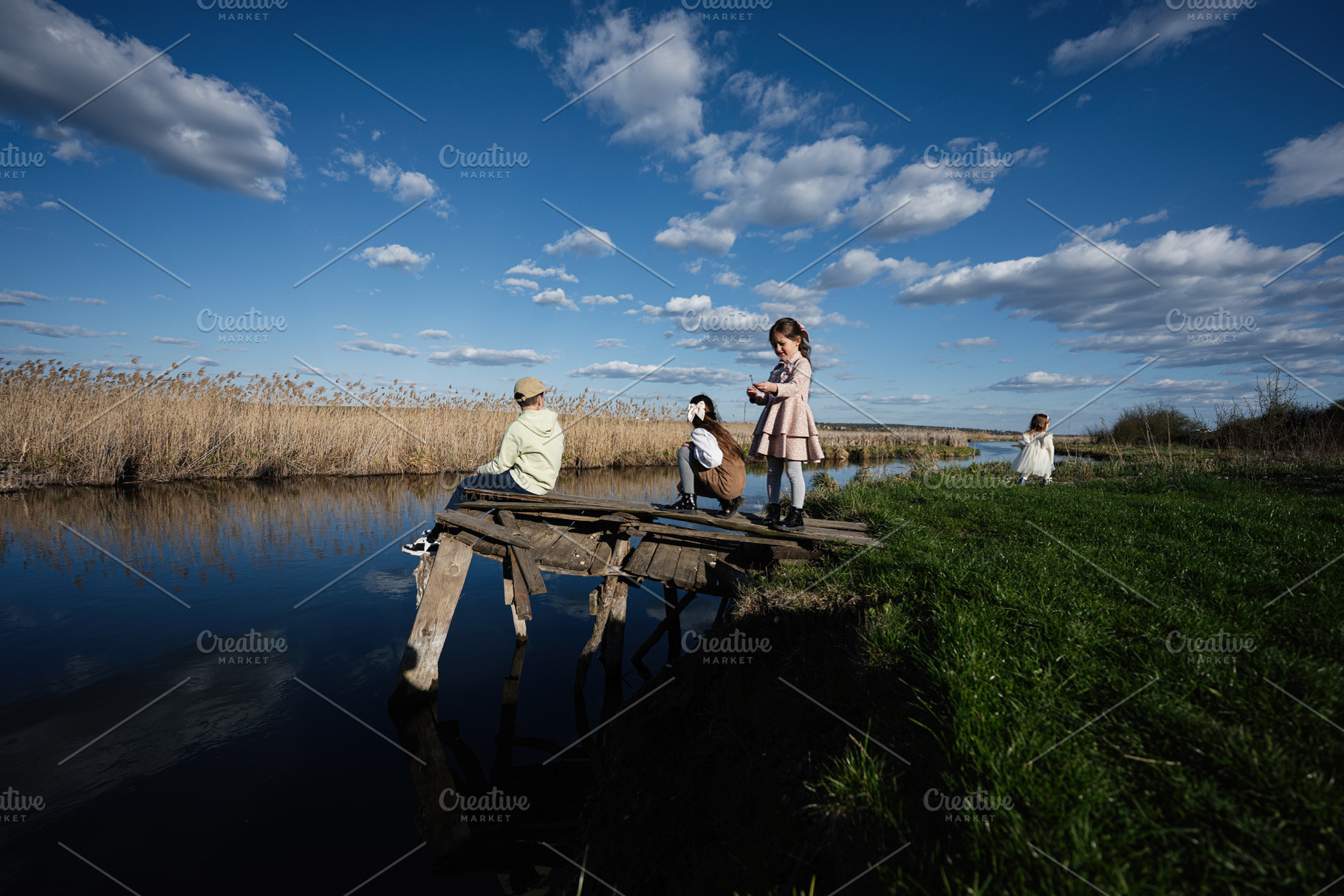 Children playing on a weathered wooden dock by a quiet river in the countryside, a Person Photo by AS photostudio