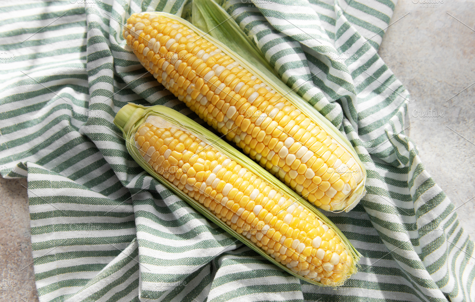 Fresh sweet corn cobs on striped cloth, a Food & Drink Photo by Olena Rudo