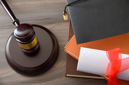 Educational trial with gavel, books, and mortarboard isolated on
