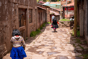 Andean girl and woman walking in a village on Taquile Island, an Architecture Photo by GoodGoods