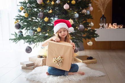 A girl with gifts plays near the Christmas tree., a Holiday Photo by Olena Rudo