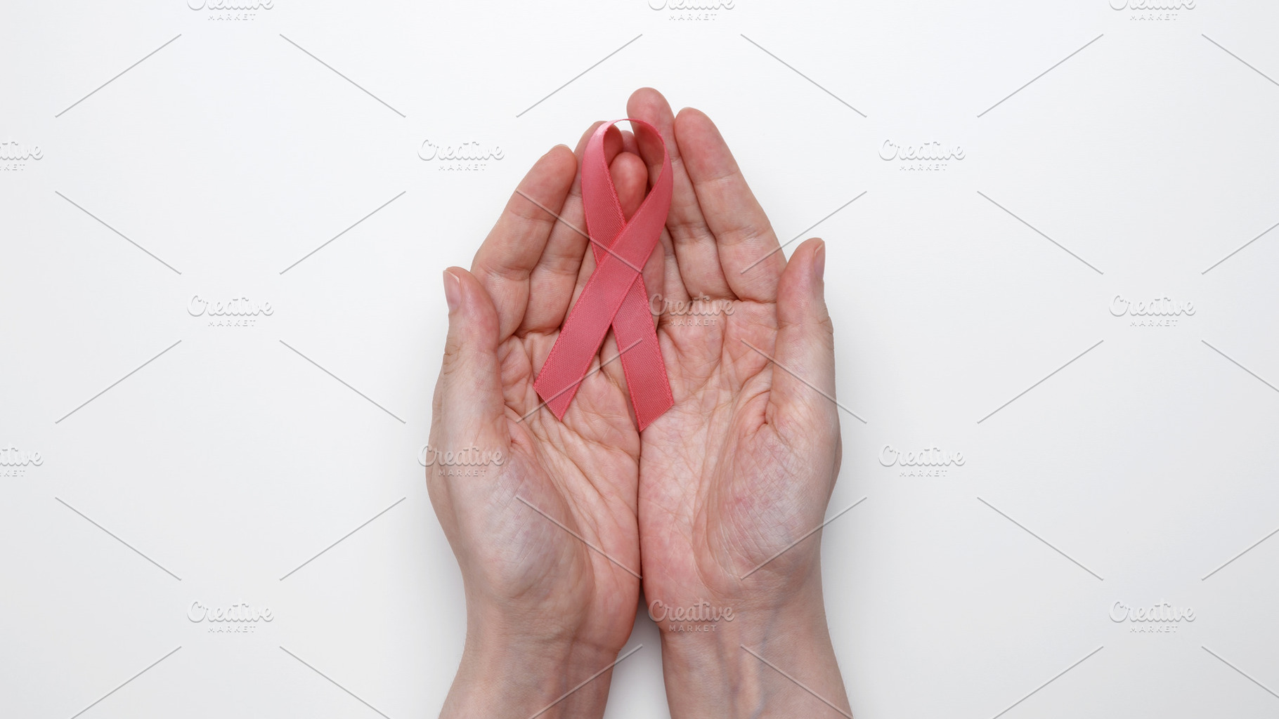 Pink awareness ribbon held gently in female hands for breast cancer advocacy, a Photo by matucha