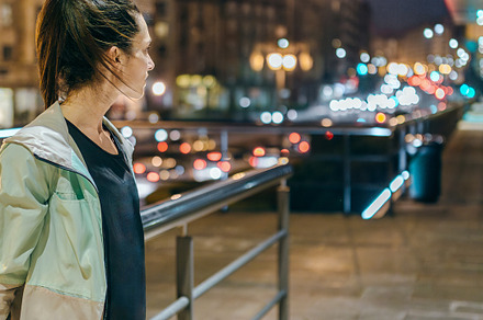 Woman wearing sportswear looking to empty sidewalk at night in t