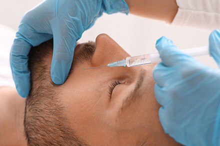 Closeup of middle-aged man getting nasolabial injection at clinic, a Photo by Prostock-Studio