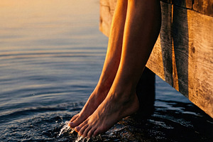 Legs Dipping in Tranquil Lake Water, a Person Photo by Virgo Studio