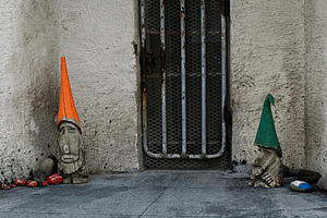 Two carved gnomes outside a wall in Akranes, Iceland near a gate, a Photo by AS photostudio
