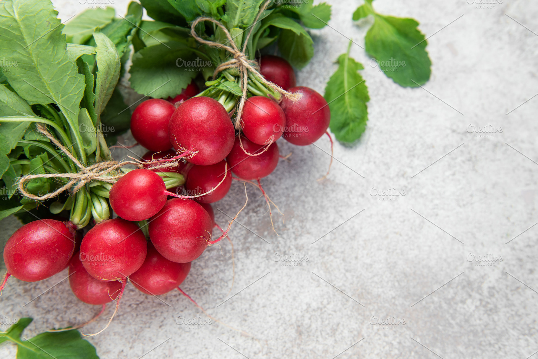 Fresh radish bunches with green leaves on stone background, a Food & Drink Photo by Olena Rudo