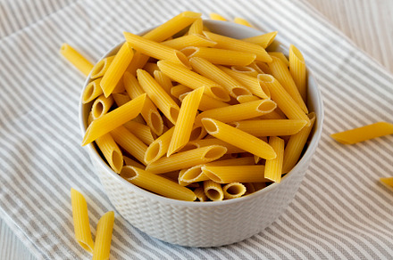 Uncooked Organic Penne Pasta in a Bowl, side view., a Food & Drink Photo by LiudmylaChuhunova
