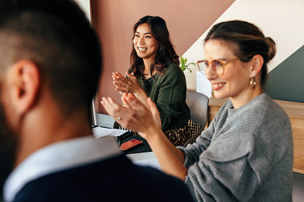 Cheerful businesspeople applauding during a meeting, a Person Photo by Jacob Lund