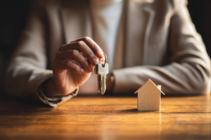 Holding keys in front of house model, a Photo by Beautiful things