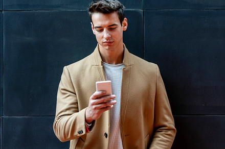 Businessman texting on mobile phone against wall, a Person Photo by RF Images