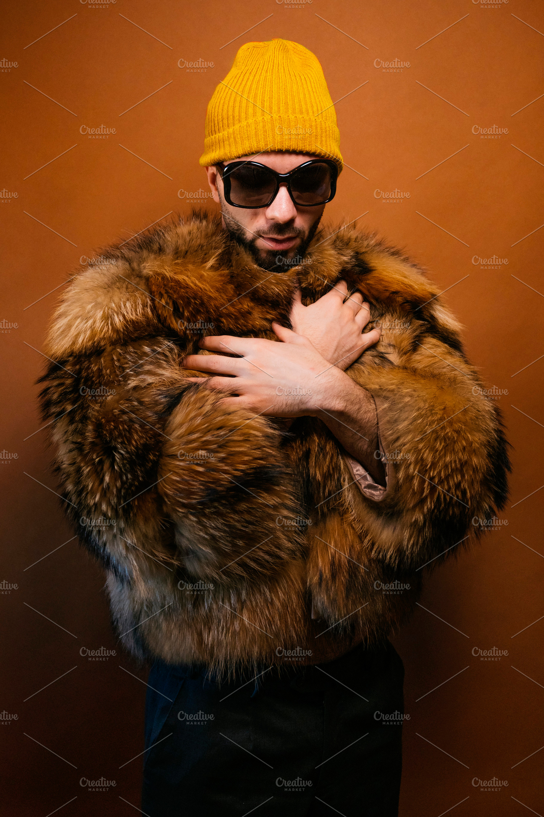 Stylish man wearing a yellow beanie, sunglasses, and fur coat, a Photo by karrastock