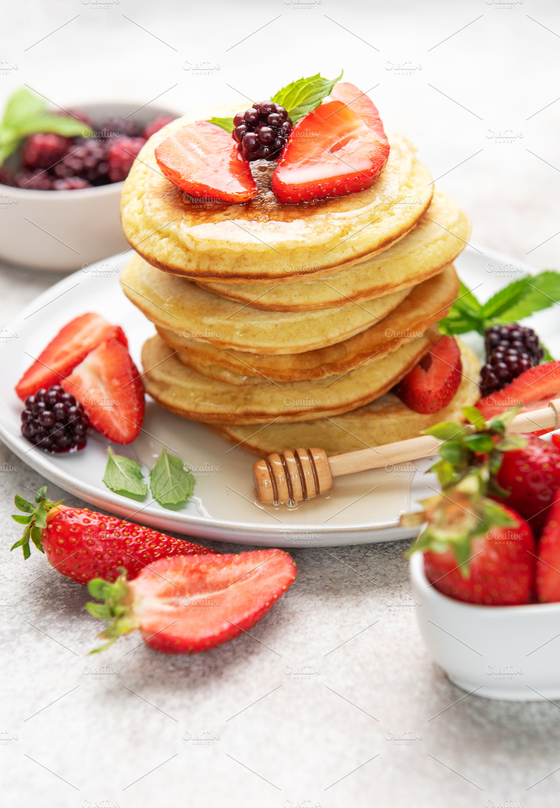 Stack of pancakes with berries, honey, and mint, a Food & Drink Photo by Olena Rudo