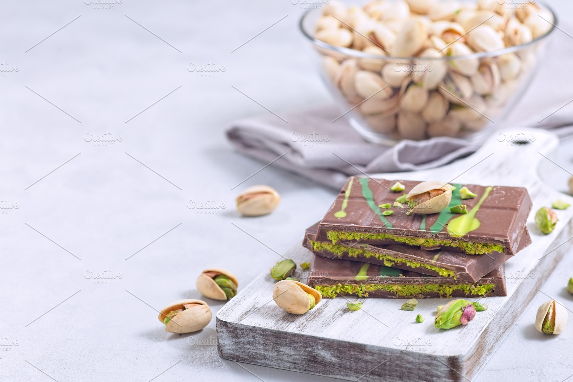 Milk chocolate bar with pistachio and kadaifi filing, lying on cutting board, h, a Food & Drink Photo by iuliia_n