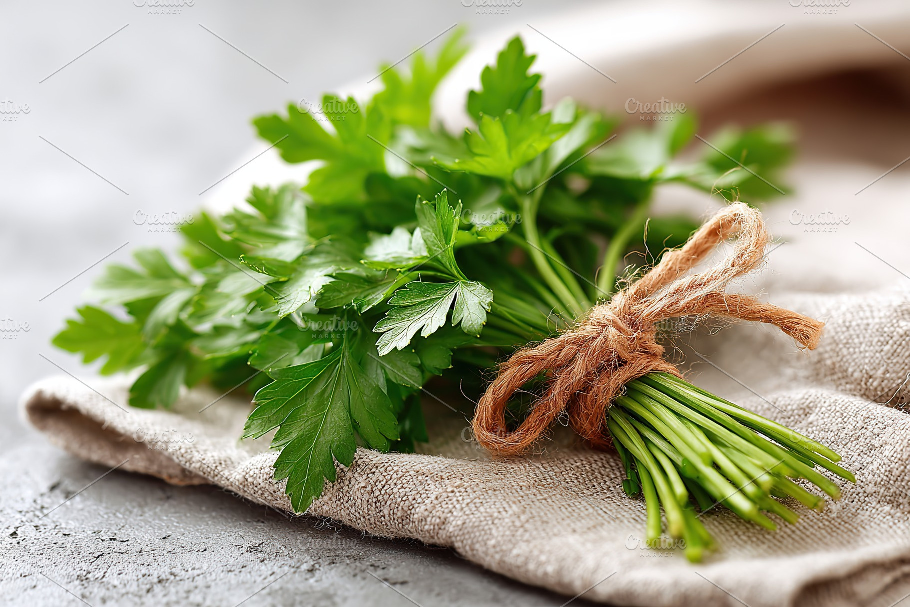 Fresh Italian flat-leaf parsley tied with twine on a rustic cloth background, a Food & Drink Photo by AlyaAnd