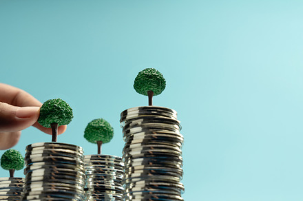 Hand putting Mini trees to growing on coin stacks symbolizing su