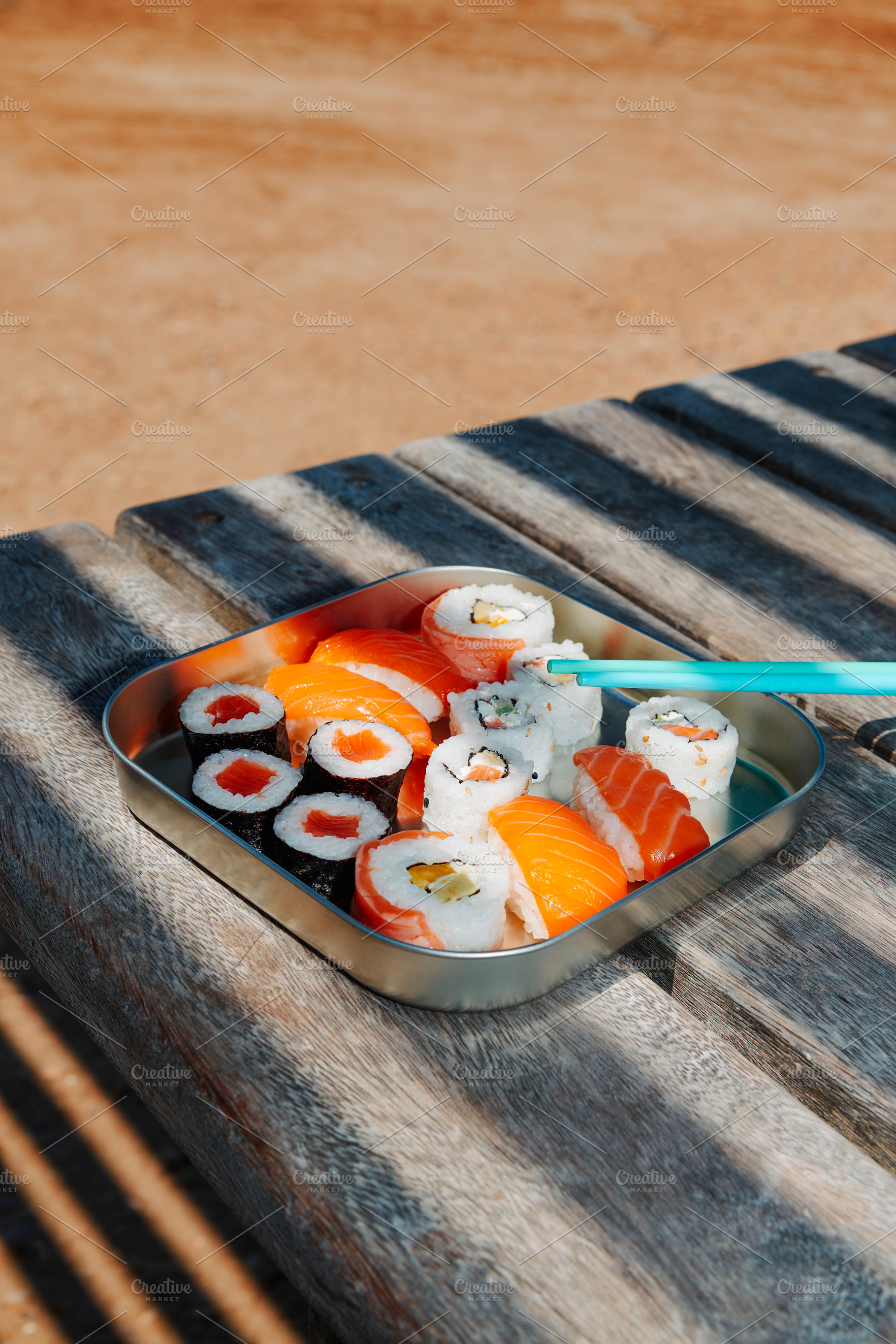 sushi and nigiri fill a metal lunch box on a table, a Photo by Nito