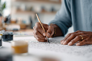 Artist creates detailed decorative lettering in a cozy studio space during dayl, a Photo by AlyaAnd