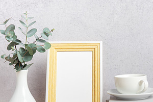 Empty photo frame, eucalyptus leaves, books and coffee cup on ta, a Background Photo by Olena Rudo