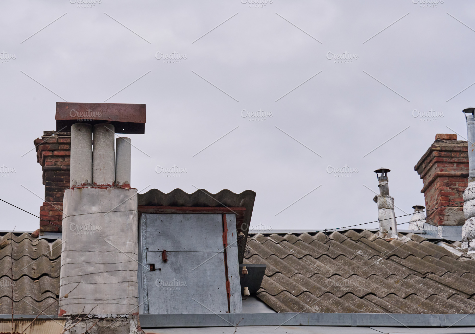 A close-up shot of several weathered chimneys on a rooftop, vary, an Architecture Photo by ndanko