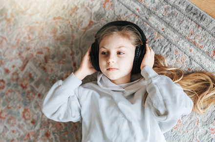 Little girl listening music lying on the floor, a Person Photo by Olena Rudo