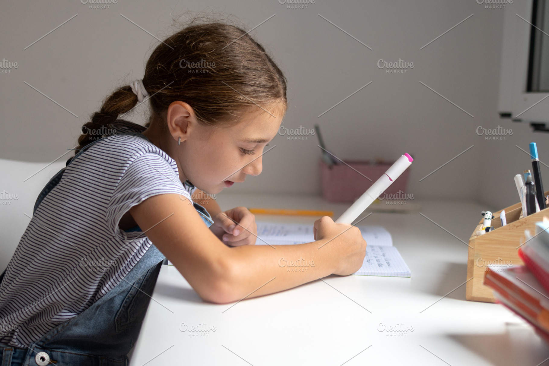 Smiling schoolgirl reading a notebook while studying at home, a Person Photo by etorres69