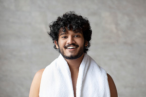 Excited bearded indian guy with towel on shoulders posing in bathroom and smili, a Person Photo by Prostock-Studio