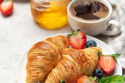 Delicious breakfast with croissants, coffee, berries and honey e